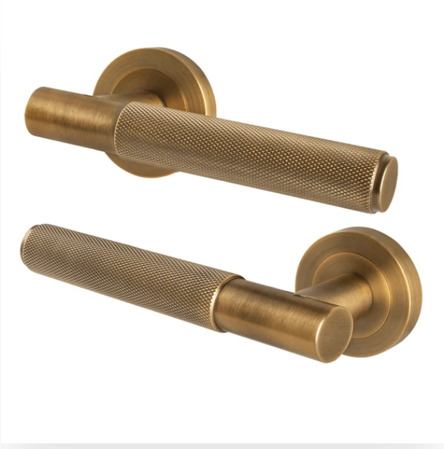 Brass knurled bar door handle on a round rose